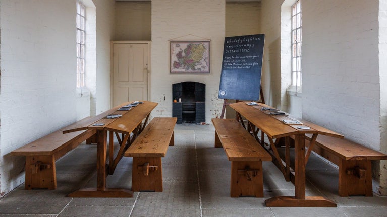 The school room with rows of desks and a blackboard in the background